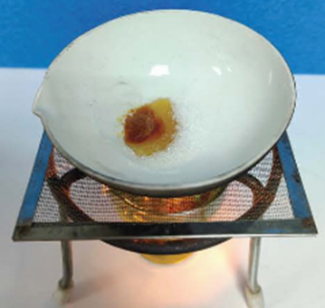 Một học sinh cho đường vào chảo và đun nóng. Ban đầu đường nóng chảy, sau đó chuyển dần sang màu nâu và có mùi đặc trưng. Đường được đun nóng (ảnh 1)