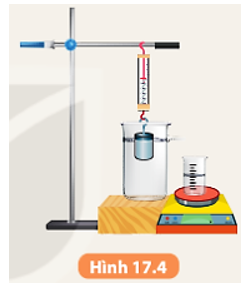 Dụng cụ: - Một lực kế có giới hạn đo 2 N; - Cân điện tử; - Quả nặng bằng nhựa 130 g; - Bình tràn; ống đong; giá thí nghiệm. Tiến hành thí nghiệm: - Treo quả nặng vào lực kế được móc trên giá thí nghiệm. Số chỉ của lực kế là P. - Nhúng quả nặng vào bình tràn đựng đầy nước (Hình 17.4).   - Khi nước từ bình tràn chảy ra ống đong đạt giá trị 20 cm3, đọc giá trị F1 trên lực kế. - Ghi giá trị lực đẩy Archimedes có độ lớn P – F1 vào vở theo mẫu Bảng 17.1. - Dùng cân điện tử đo khối lượng nước từ bình tràn chảy ra ống đong và tính trọng lượng của lượng nước đó, ghi vào vở theo mẫu Bảng 17.1. - Tiếp tục nhúng quả nặng chìm xuống khi nước trong bình tràn chảy ra lần lượt là 40 cm3, 60 cm3, 80 cm3, xác định độ lớn lực đẩy Archimedes và trọng lượng của lượng nước tràn ra tương ứng. Ghi vào vở theo mẫu Bảng 17.1. - Thay nước bằng nước muối đặc và lặp lại thí nghiệm. - So sánh trọng lượng của lượng chất lỏng tràn ra với lực đẩy Archimedes tương ứng.   Từ bảng số liệu ta có thể rút ra được kết luận gì về độ lớn lực đẩy Archimedes. (ảnh 1)