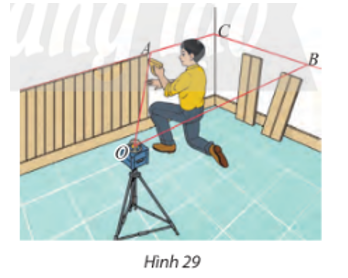 Trong xây dựng, người ta thường dùng máy quét tia laser để kẻ các đường thẳng trên tường hoặc sàn nhà. Tìm giao tuyến của mặt phẳng tạo bởi các tia laser OA và OB của các mặt tường trong Hình 29.  (ảnh 1)