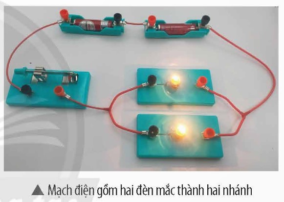 Ở mạch điện trong hình bên, nếu một trong hai đèn bị hỏng thì đèn kia còn sáng không? (ảnh 1)