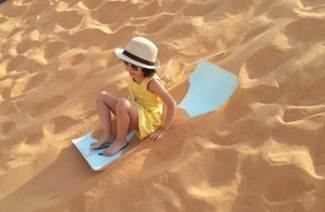 A child sitting on a sled in the sand
AI-generated content may be incorrect.
