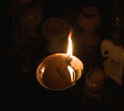 A lit oil lamp in a dark room

AI-generated content may be incorrect.