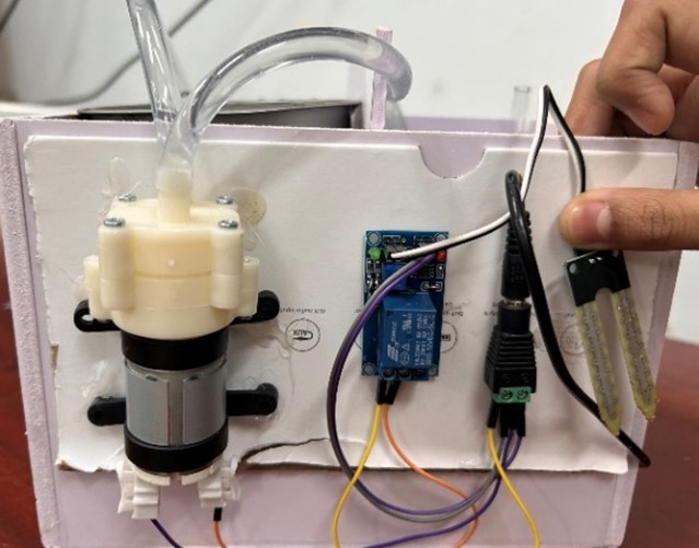 Hình 4 là một mạch điện điều khiển sử dụng mô đun cảm biến của một nhóm học sinh lớp 8/4 trường THCS Nguyễn Du thực hiện. Trong mạch điện có sử dụng mô đun cảm biến độ ẩm và máy bơm.  (ảnh 1)